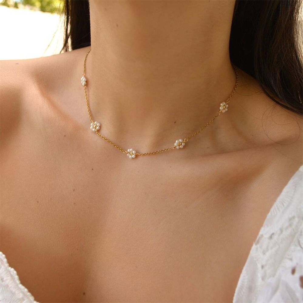 Le cou d'une femme avce un collier ras de cou à motif marguerite.