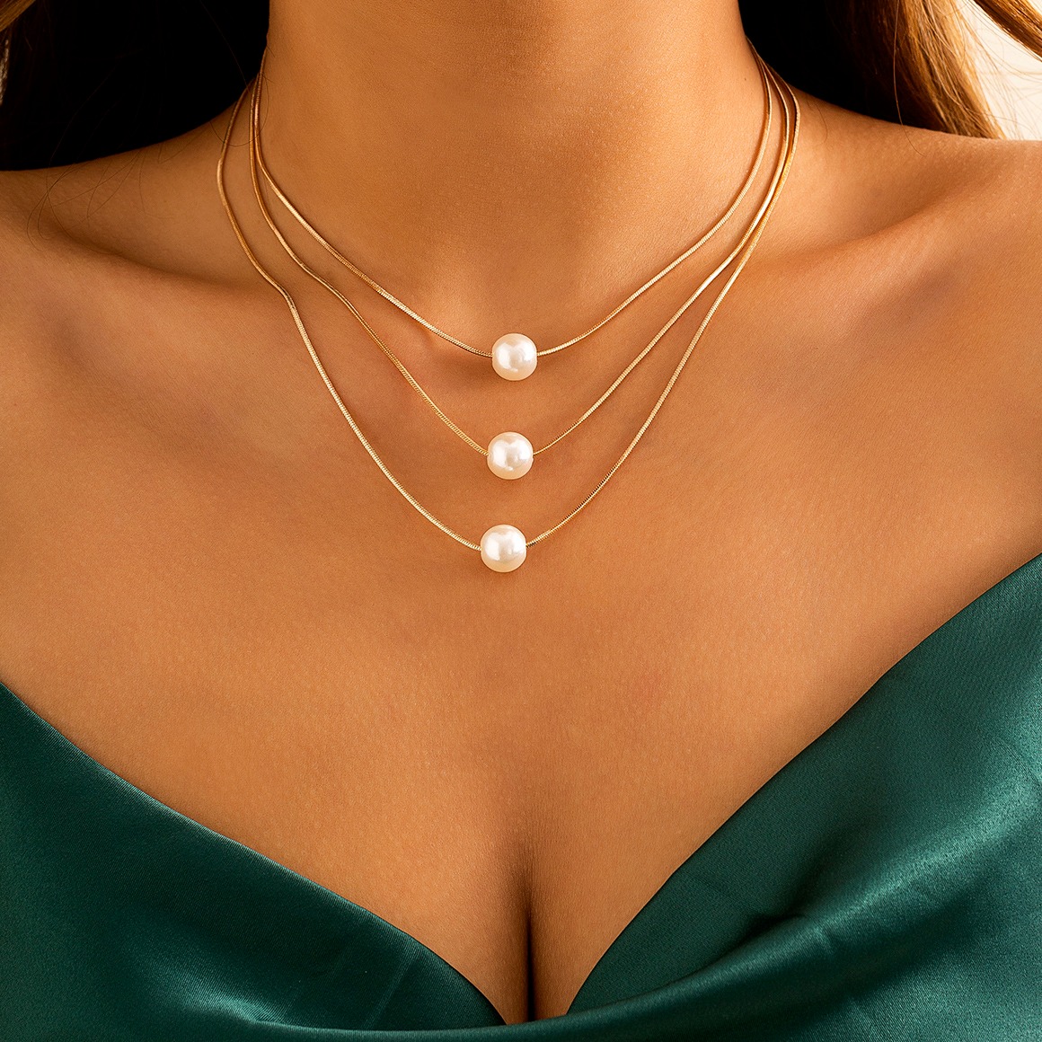 Collier ras de cou triple chaîne pendentifs perles porté autour du cou d'une femme.